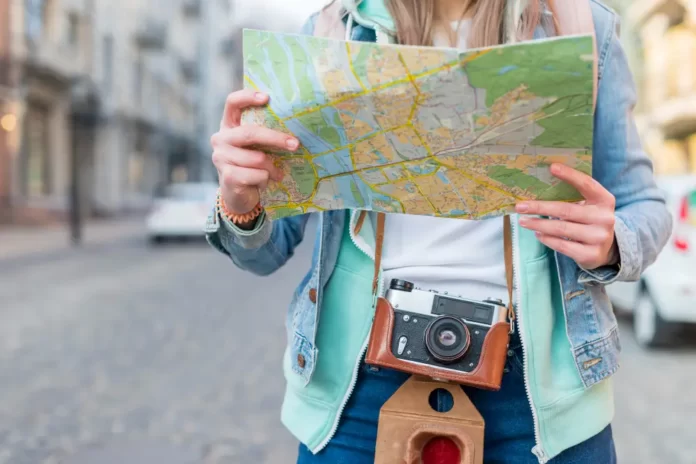 mid-section-female-traveler-with-camera-holding-map-hand