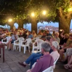 Pubblico seduto sotto i tigli ad Arzengio durante la presentazione del libro sul Sessantotto